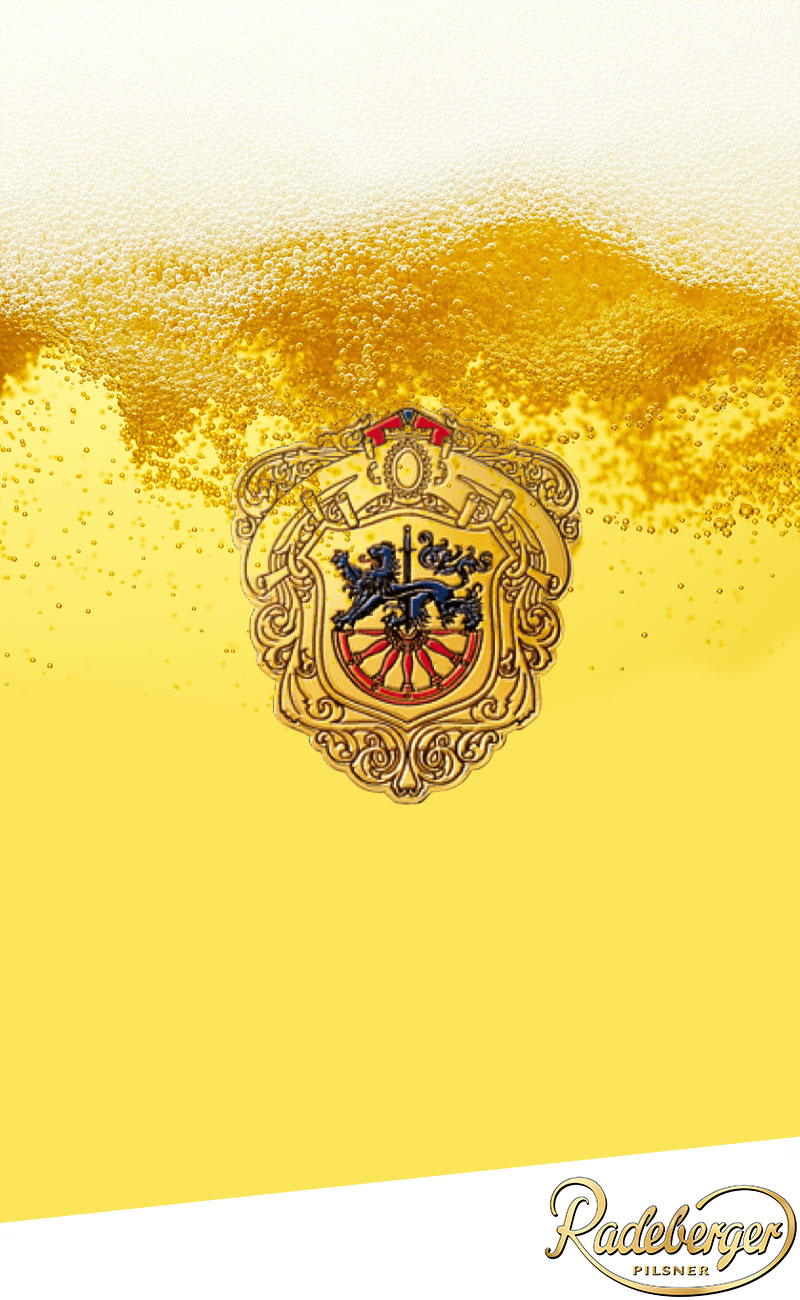 Ein goldenes Bier mit aufsteigenden Bläschen, mit einem verzierten Wappen in der Mitte und dem Vollblut Radeberger Pilsner-Logo in der unteren rechten Ecke.
