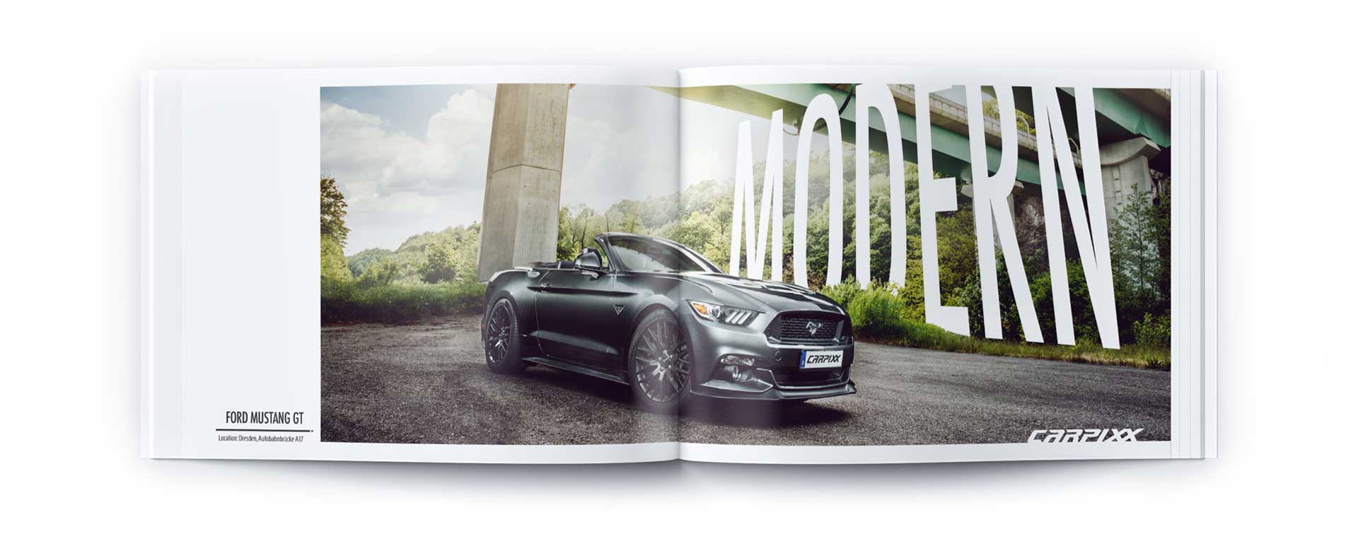 An einem sonnigen Tag parkt ein schwarzes Ford Mustang GT Cabrio unter einer Brücke. Dahinter steht in fetten weißen Buchstaben „MODERN“ – ein schnittiger Vollblut-Carpixx-Moment, festgehalten in einer offenen Autobroschüre.